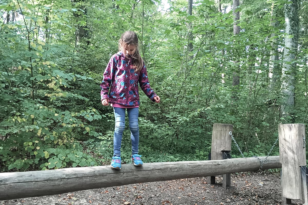 Kind balanciert auf Baumstamm