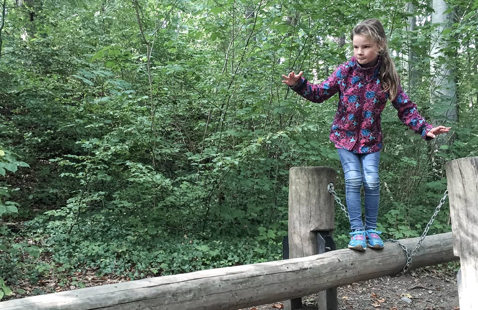 Kind balanciert auf Baumstamm